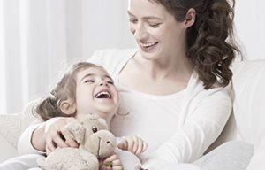 Una mujer con un niño en brazos; el niño sostiene un peluche.